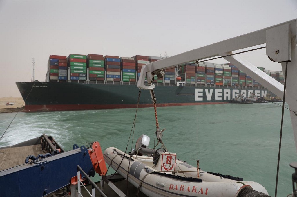 A handout picture released by the Suez Canal Authority on March 25, 2021 shows  Egyptian tug boats trying to free Taiwan-owned cargo MV Ever Given (Evergreen), a 400-metre- (1,300-foot-)long and 59-metre wide vessel, lodged sideways and impeding all traffic across the waterway of Egypt's Suez Canal. - Egypt's Suez Canal Authority said it was "temporarily suspending navigation" until refloating of the MV Ever Given ship was completed on one of the busiest maritime trade routes. (Photo by - / Suez CANAL / AFP)