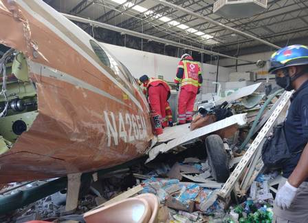 Equipes de resgate fazem buscas dentro do avião, que destruiu parte do supermercado
